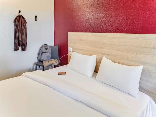 a bed with two pillows and a backpack in a room at hotelF1 Chaumont in Chaumont