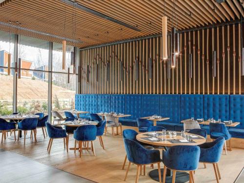 a dining room with blue chairs and tables in a room at Tarcin Forest Resort & Spa Sarajevo - MGallery Collection in Tarčin