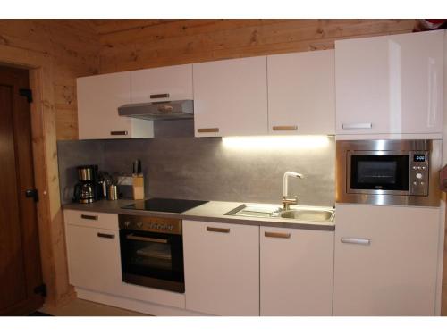 a kitchen with white cabinets and a sink and a microwave at Feriendorf X-Alp Lodges Ötztal in Sautens