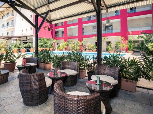 a patio with tables and chairs and a pool at Mercure Cayenne Royal Amazonia in Cayenne