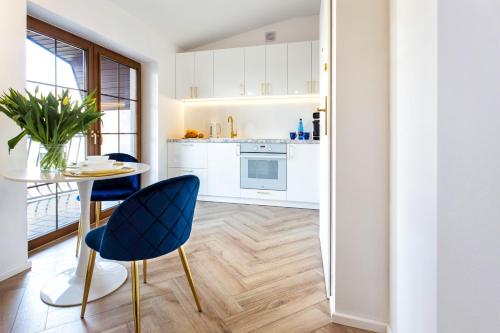 eine Küche mit weißen Schränken sowie einem Tisch und Stühlen in der Unterkunft Apartament BIANCO BLU pod Jasną Górą. in Częstochowa