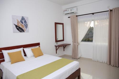 a bedroom with a bed and a window at Amadel Negombo in Negombo