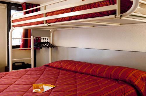 Premiere Classe Roanne Perreux في Perreux: غرفة نوم مع سرير وبطانية حمراء وسرير بطابقين