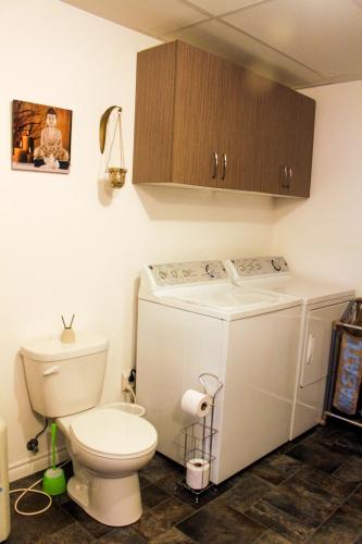 a bathroom with a white toilet and a washer at Casa Linda Victoriaville in Princeville