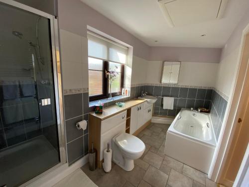 a bathroom with a toilet and a tub and a sink at The Stable - 2 bed annexe, near Longleat in Warminster