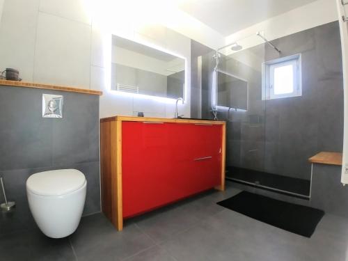 La salle de bains est pourvue de toilettes et d'une armoire rouge. dans l'établissement Le Moulin de Felix, à Robion