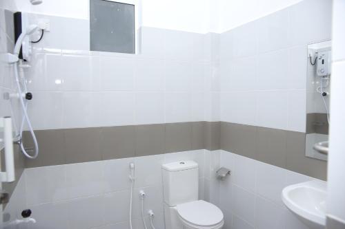 a white bathroom with a toilet and a sink at Amadel Negombo in Negombo