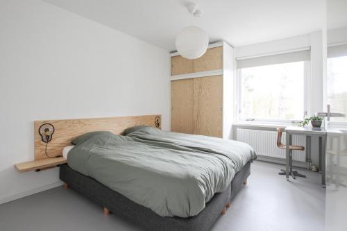 a bedroom with a bed and a desk and a window at Vakantiehuis Drie Dennen in Bergen