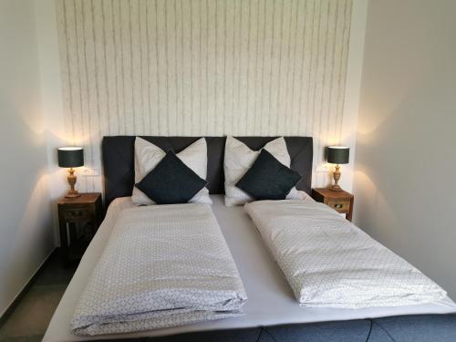 ein großes Bett mit zwei Kissen und zwei Lampen in der Unterkunft Heeser Hof - Urlaub im Grünen in Weeze