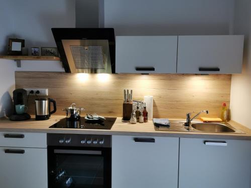 a kitchen with white cabinets and a stove and a sink at Heeser Hof - Urlaub im Grünen in Weeze