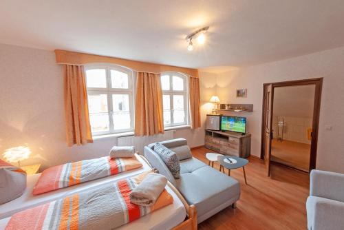 a bedroom with a bed and a couch and a tv at Alte Schule Café und Pension in Fürstlich Drehna