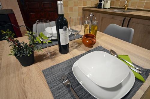 a table with a white plate and a bottle of wine at PORTAL DE MOLINA 2 - Piso acogedor en el casco histórico de Albarracín in Albarracín