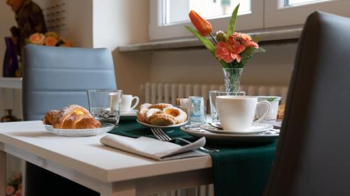 een tafel met croissants en bekers en een vaas met bloemen bij Maison Gentile in Lucca