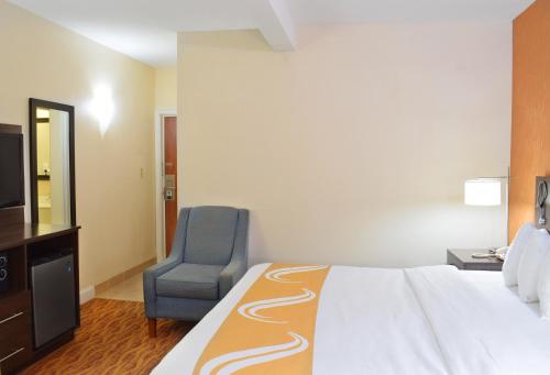 a hotel room with a bed and a chair at Quality Inn & Suites Middletown - Newport in Middletown