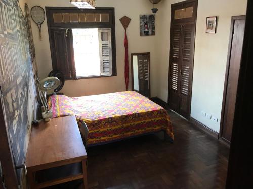 a bedroom with a bed and a table and a window at Charme do Poço in Recife
