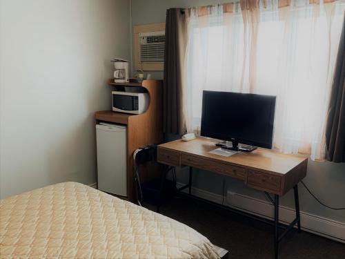 a bedroom with a desk with a computer monitor on it at Hawberry Motel in Little Current