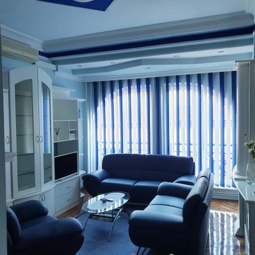 a living room with blue couches and a tv at Blue apartman in Sombor