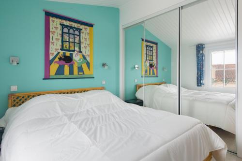 a blue bedroom with two beds and a mirror at Maison Amande in La Flotte