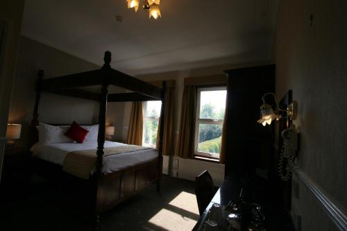 ein Schlafzimmer mit einem Himmelbett und einem Fenster in der Unterkunft Grange Moor Hotel in Maidstone