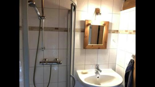 ein Bad mit einem Waschbecken und einer Dusche mit einem Spiegel in der Unterkunft Ferienhaus in Arendsee mit direkter Seenähe in Arendsee
