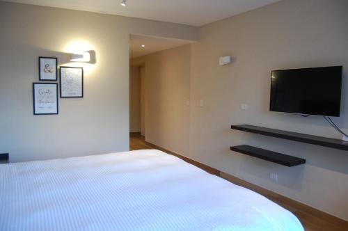 Avellaneda Aparts & Suites في بوينس آيرس: غرفة نوم بسرير وتلفزيون بشاشة مسطحة