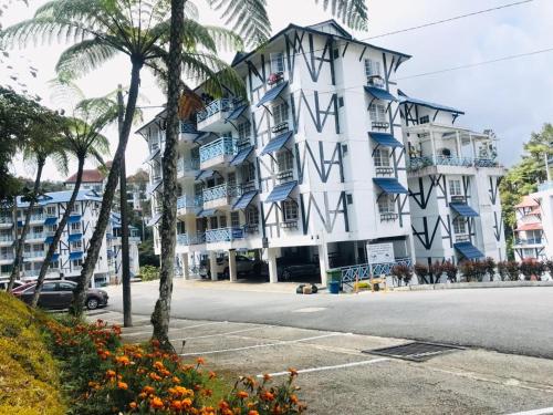 a large white building with blue balconies on a street at MERLIN HOME DESA ANTHURIUM in Tanah Rata