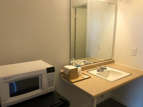 a microwave sitting on a bathroom counter with a sink at Royal Inn in Port Lavaca