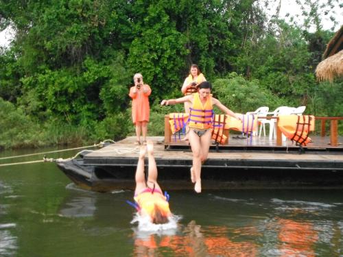 Un groupe de personnes sautant d'un quai dans l'eau dans l'établissement Star Hill River Kwai Resort, à Ban Kaeng Raboet