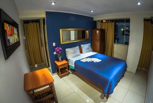 a bedroom with a bed with a blue bedspread at Hotel Casa Maldonado in Ica