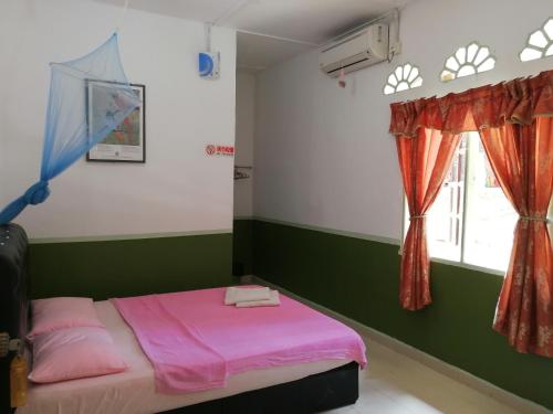 a bedroom with a pink bed and a window at Delimah guesthouse in Kuala Tahan