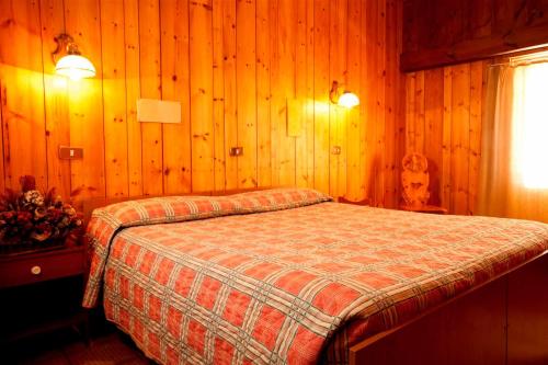 a bedroom with a bed in a wooden wall at Hotel Ristoro Vagneur in Saint Nicolas