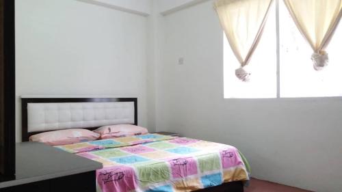 a bedroom with a bed with a colorful comforter at MERLIN HOME DESA ANTHURIUM in Tanah Rata