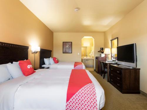 a hotel room with two beds and a flat screen tv at OYO Hotel Valley View TX, I-35 in Valley View