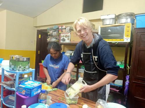 two people standing in a kitchen preparing food at Chacha Homestay & Dormitory in Ruteng