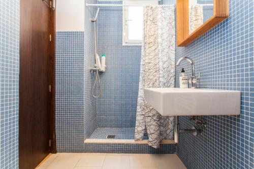 W wyłożonej niebieskimi kafelkami łazience znajduje się umywalka i prysznic. w obiekcie LF PARKING INCLUIDO Amplio Loft en Barrio Santa Cruz w Sewilli