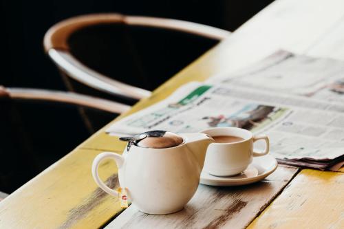 two cups of coffee on a wooden table with a newspaper at Port Macquarie Hotel in Port Macquarie