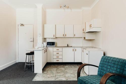 a kitchen with white cabinets and a blue chair at Port Macquarie Hotel in Port Macquarie