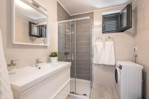 ein Bad mit einem Waschbecken und einer Glasdusche in der Unterkunft Lemon Tree Dubrovnik Apartments in Dubrovnik