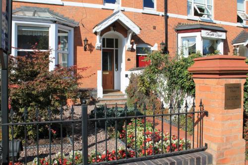 a brick house with a black fence and flowers at Virginia Lodge in Stratford-upon-Avon