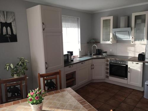 eine Küche mit weißen Schränken, einem Tisch und einem Fenster in der Unterkunft Spreewald-Ferienwohnung Jahn in Radensdorf
