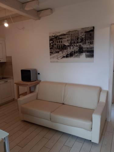 ペスキエーラ・デル・ガルダにあるSweet Appartment di Guidoの白いソファ付きのリビングルーム(壁に絵画付)