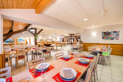 une salle à manger avec des tables et des chaises en bois dans l'établissement Village vacances Chalet de la Haute-Joux, à Cerniébaud