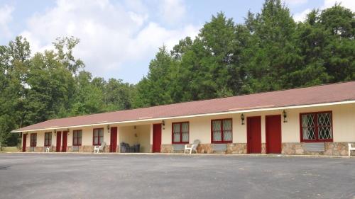 a building with red and white walls and trees at Valley Inn - Hamilton Ga in Hamilton