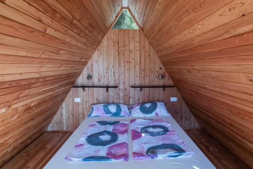 a bed in a room with a wooden wall at Glamping Tinka in Tolmin