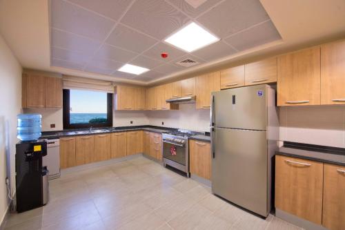 a large kitchen with wooden cabinets and a refrigerator at Private 003 - Property Advisers in Dibba