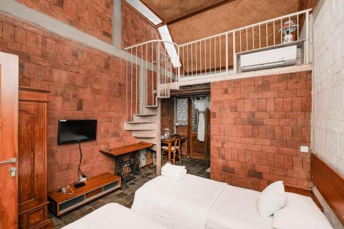 a brick walled room with a bed and a staircase at Djajanti House in Semarang