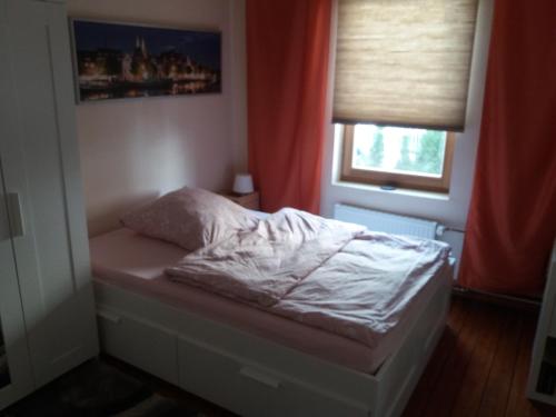 uma pequena cama num quarto com uma janela em Pensionszimmer Lützowzimmer em Lübeck