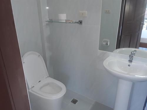 a white bathroom with a toilet and a sink at Adayo Cove Resort in Siquijor