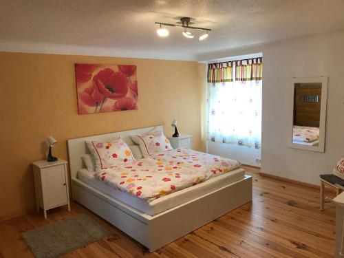 1 dormitorio con 1 cama y una pintura floral en la pared en Sanierte möblierte Altbauwohnung am Waldrand für bis zu 6 Personen en Borkheide