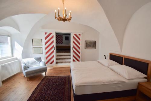 um quarto com uma cama, uma cadeira e um lustre em Sammer Residenz, Breitenbrunn am Neusiedlersee em Breitenbrunn